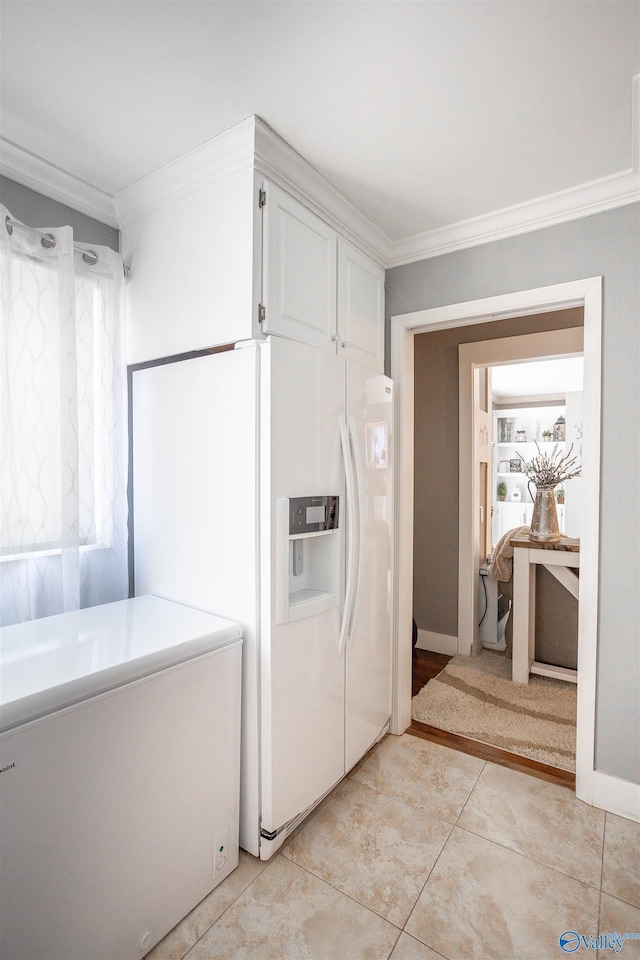 interior space with light tile patterned flooring, refrigerator, ornamental molding, white fridge with ice dispenser, and white cabinets