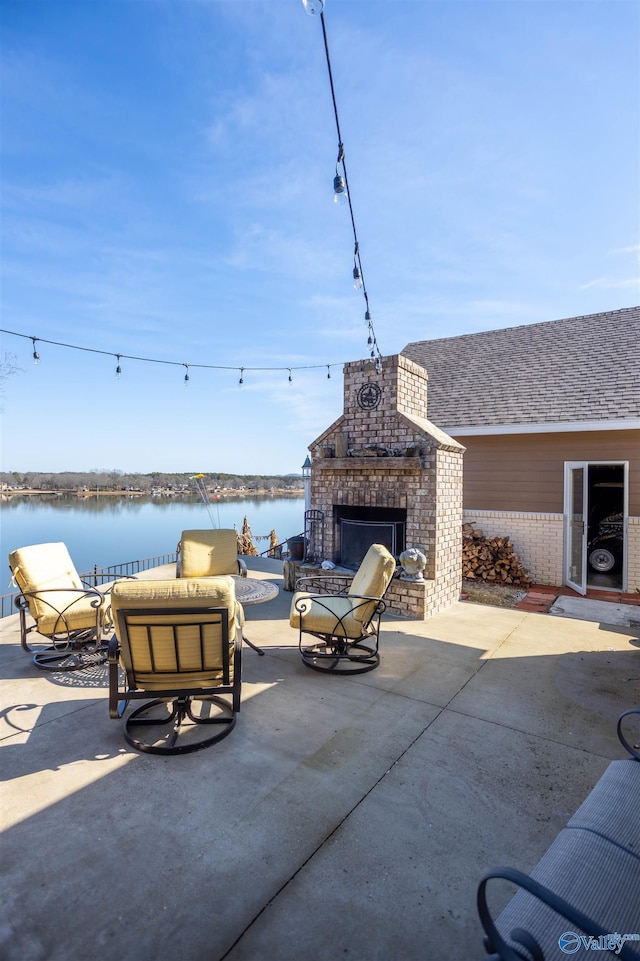 view of patio with a water view and an outdoor living space with a fireplace