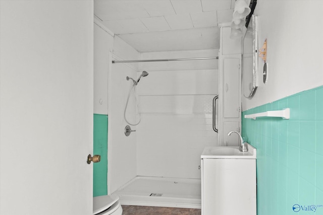 bathroom with tile walls, vanity, tiled shower, and toilet