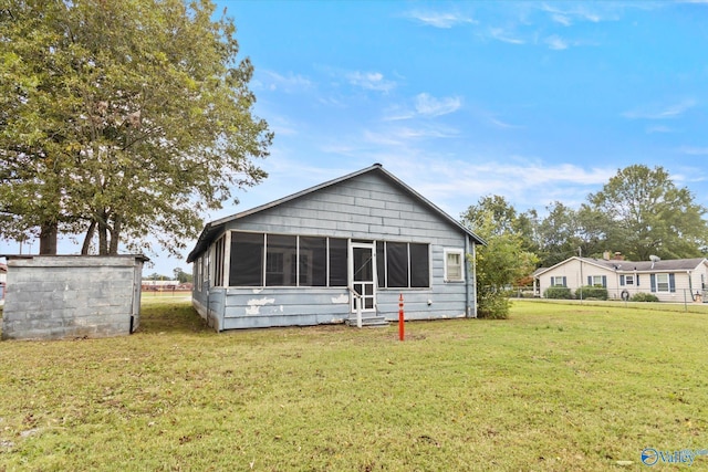 rear view of property featuring a yard and a sunroom