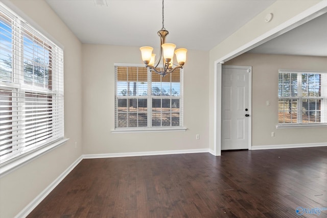 unfurnished dining area with dark wood-type flooring, plenty of natural light, and a notable chandelier