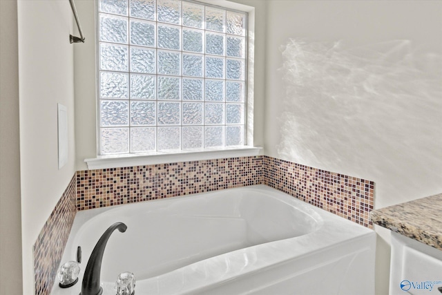 bathroom with vanity, a wealth of natural light, and a bathtub