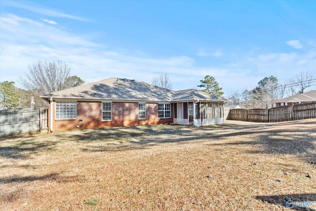 rear view of house with a sunroom and a lawn