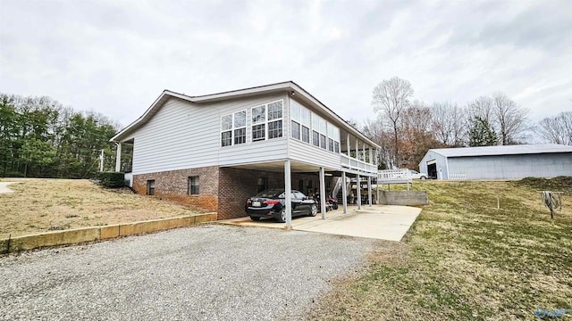 exterior space featuring brick siding, a lawn, and gravel driveway