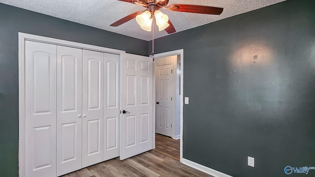 unfurnished bedroom featuring hardwood / wood-style flooring, ceiling fan, a textured ceiling, and a closet