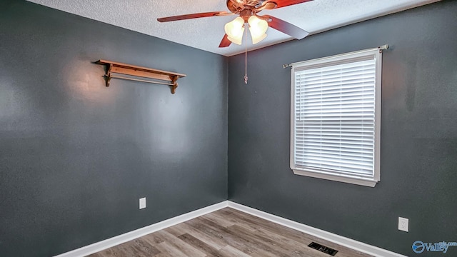 spare room featuring wood-type flooring, ceiling fan, and a textured ceiling