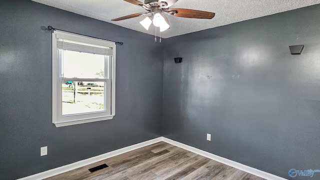 spare room featuring wood-type flooring, ceiling fan, and a textured ceiling