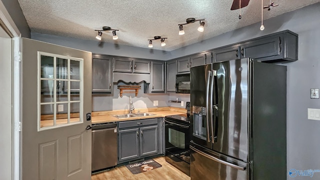 kitchen featuring wood counters, sink, a textured ceiling, light hardwood / wood-style flooring, and black appliances