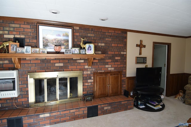 carpeted living area featuring wainscoting, crown molding, visible vents, and heating unit