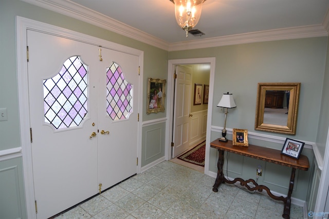 entrance foyer with light floors, ornamental molding, wainscoting, and visible vents