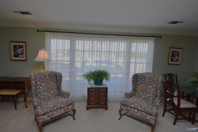 sitting room featuring visible vents, crown molding, and light colored carpet