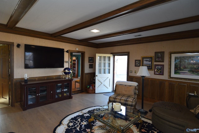 living area with a wainscoted wall, beamed ceiling, visible vents, and wood finished floors