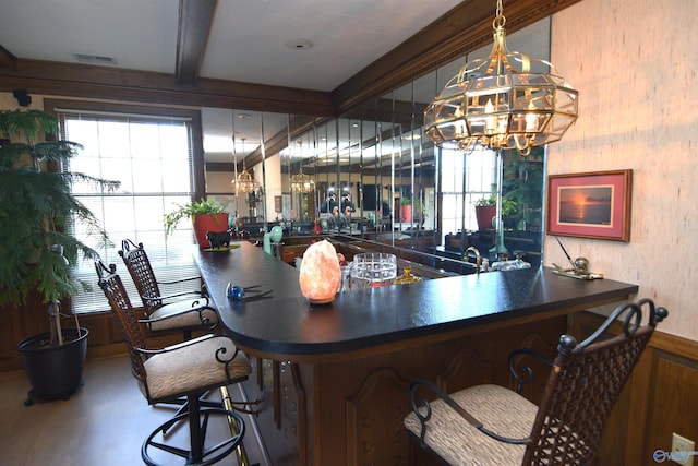 bar featuring a chandelier, visible vents, a wealth of natural light, beam ceiling, and indoor wet bar