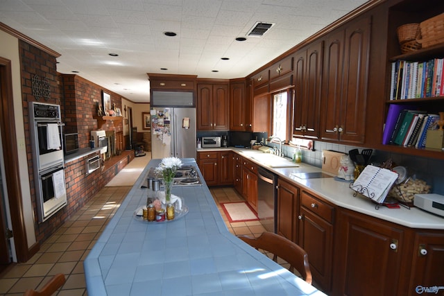 kitchen with tile counters, visible vents, appliances with stainless steel finishes, ornamental molding, and a sink