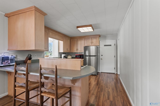 1308 Aston St, Athens, AL 35611 - kitchen with a kitchen bar, dark wood-style flooring, light brown cabinetry, freestanding refrigerator, and a peninsula