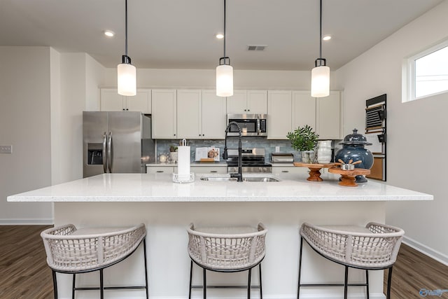 166 Mill Valley Way, New Market, AL 35761 - kitchen featuring a sink, stainless steel appliances, an island with sink, decorative backsplash, and dark wood-style floors