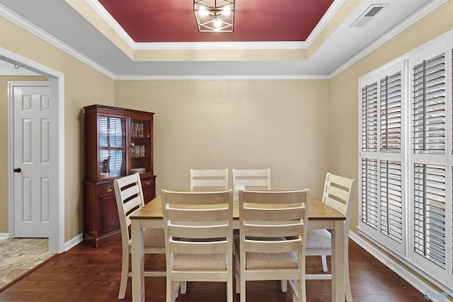 dining space with a tray ceiling, crown molding, dark wood-style floors, and visible vents