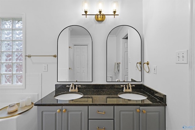 full bath with double vanity, a garden tub, and a sink