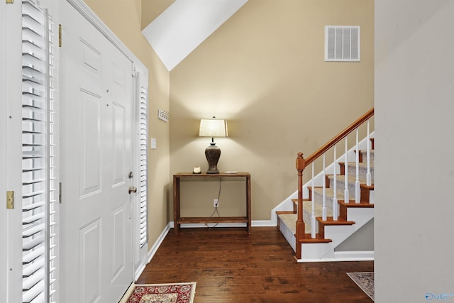 entrance foyer with visible vents, baseboards, stairway, vaulted ceiling, and hardwood / wood-style floors