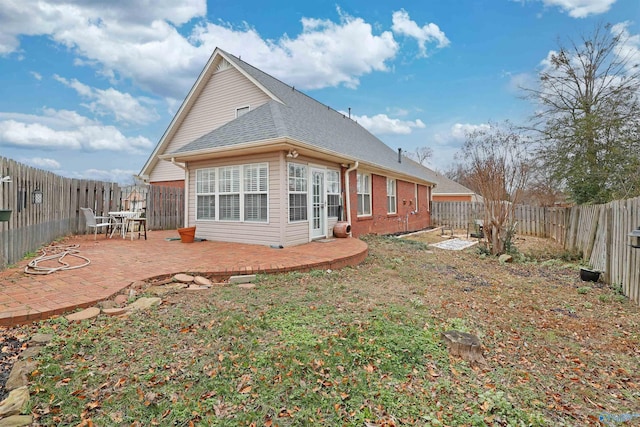 back of property with a patio area, brick siding, a fenced backyard, and roof with shingles