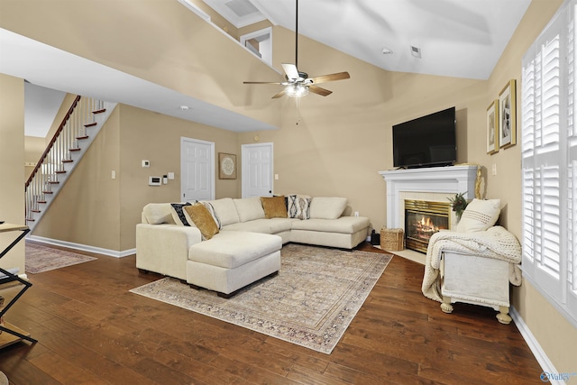living area featuring a ceiling fan, a tiled fireplace, stairway, wood-type flooring, and baseboards