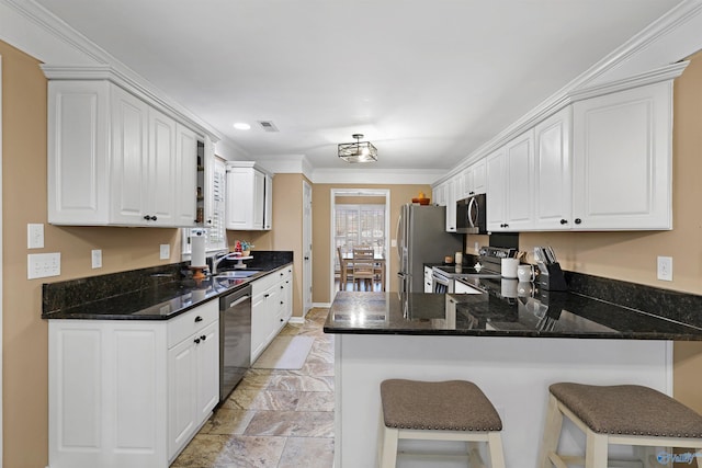 kitchen with visible vents, a peninsula, a sink, appliances with stainless steel finishes, and white cabinetry