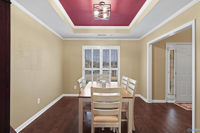 dining space with dark wood-style floors, visible vents, baseboards, and a tray ceiling