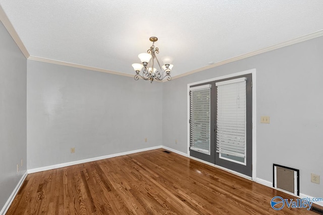 empty room featuring crown molding, hardwood / wood-style floors, a notable chandelier, and a textured ceiling