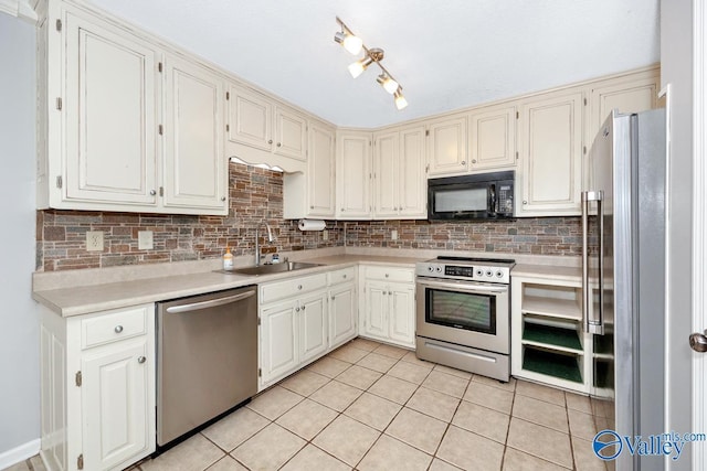 kitchen featuring light tile patterned flooring, sink, white cabinetry, stainless steel appliances, and decorative backsplash