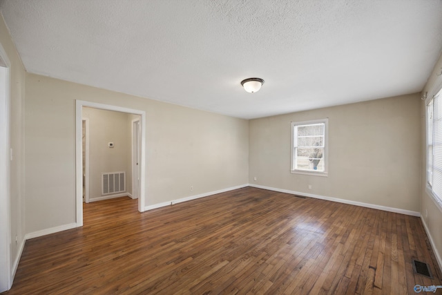 empty room featuring dark hardwood / wood-style flooring and a textured ceiling