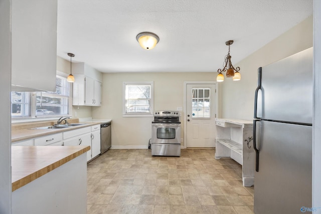 kitchen with pendant lighting, sink, white cabinets, and appliances with stainless steel finishes