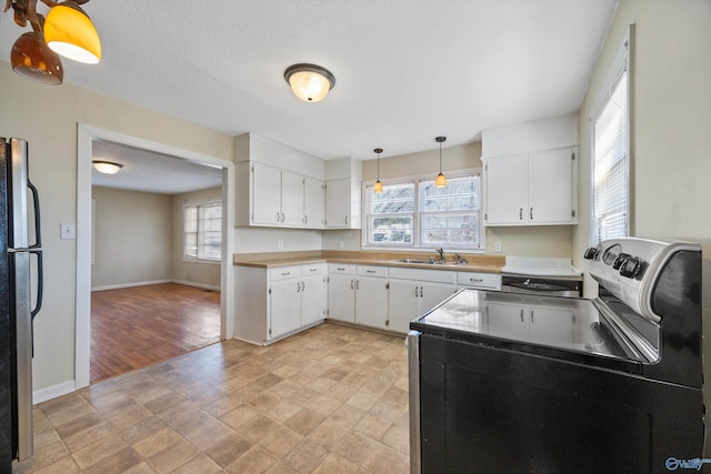 kitchen with hanging light fixtures, white cabinetry, appliances with stainless steel finishes, and sink