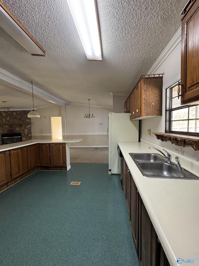 kitchen with a textured ceiling, light countertops, decorative light fixtures, and a sink