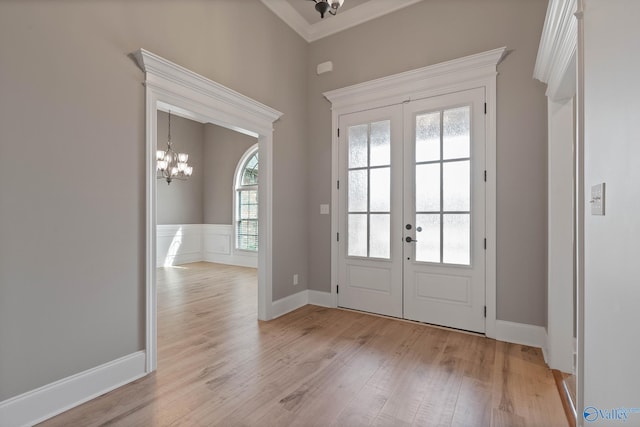 entryway with a healthy amount of sunlight, a chandelier, light hardwood / wood-style floors, and french doors