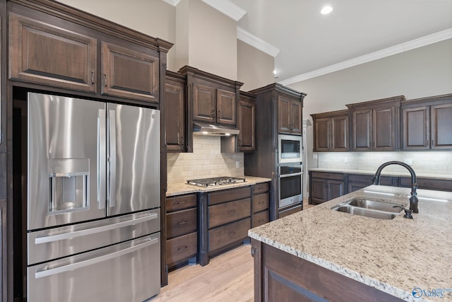 kitchen with appliances with stainless steel finishes, crown molding, sink, decorative backsplash, and light wood-type flooring