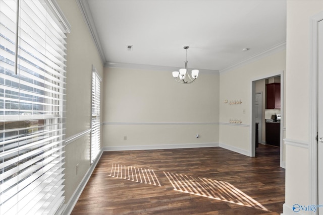 empty room featuring dark wood-type flooring, a notable chandelier, and ornamental molding