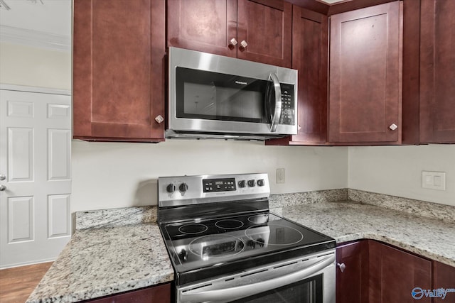 kitchen with light stone counters, hardwood / wood-style flooring, ornamental molding, and stainless steel appliances