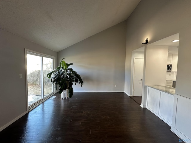 spare room featuring lofted ceiling, dark wood finished floors, and baseboards