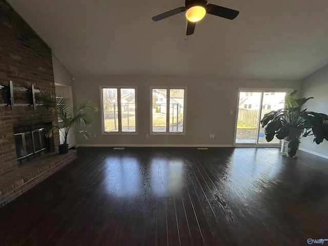 living area with lofted ceiling, a fireplace, baseboards, and wood finished floors