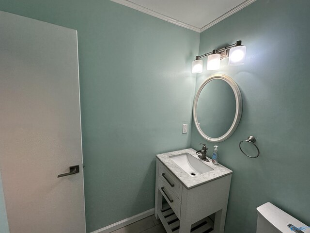 bathroom with toilet, baseboards, ornamental molding, and vanity