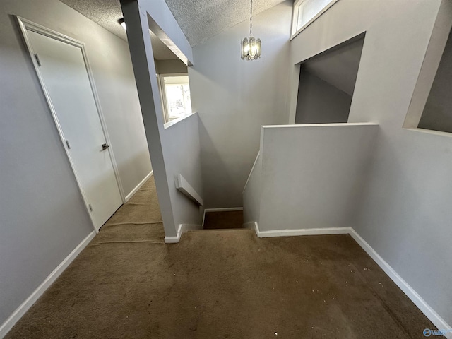 stairs with baseboards, vaulted ceiling, and a textured ceiling