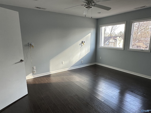 unfurnished room with dark wood-style flooring, visible vents, and plenty of natural light