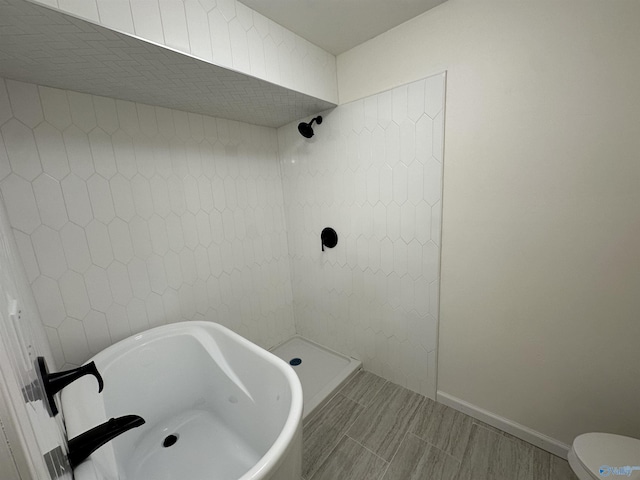 full bath with a freestanding bath, a tile shower, and baseboards