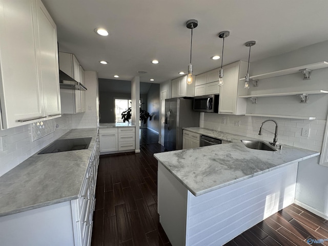 kitchen featuring wood finish floors, a sink, black appliances, a peninsula, and wall chimney exhaust hood