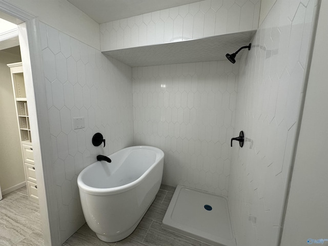 full bath featuring a freestanding bath, a tile shower, and tile walls