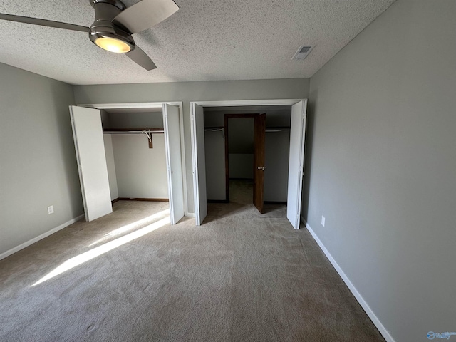 unfurnished bedroom with multiple closets, carpet flooring, visible vents, and baseboards