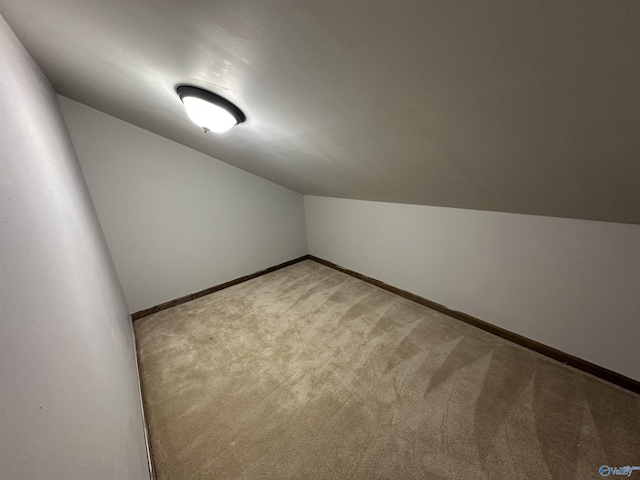 bonus room with baseboards, vaulted ceiling, and light colored carpet