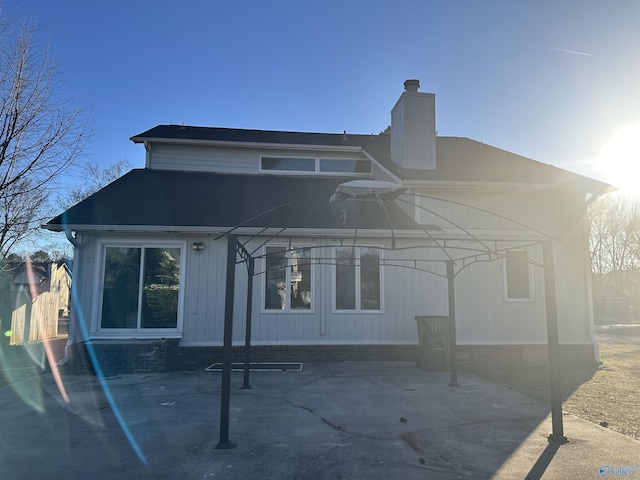 rear view of property featuring a chimney and a patio area