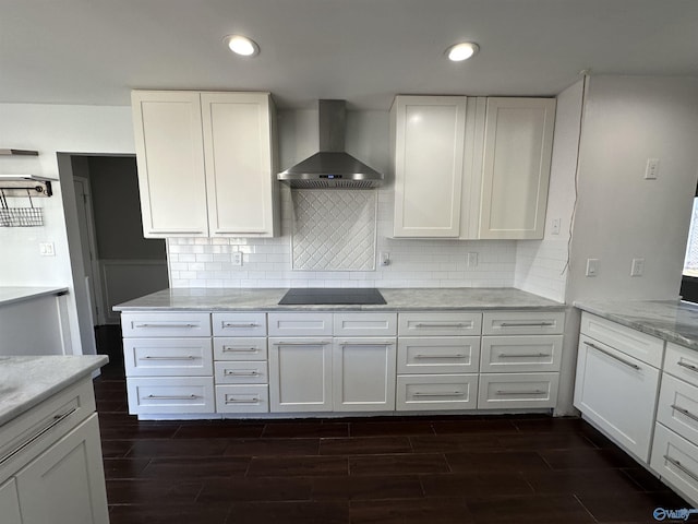 kitchen with wood tiled floor, black electric stovetop, white cabinets, and wall chimney exhaust hood