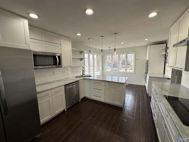 kitchen featuring a peninsula, a sink, white cabinets, appliances with stainless steel finishes, and open shelves